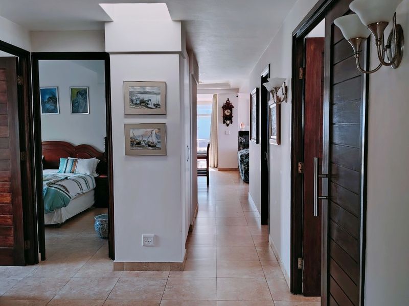 A well-lit hallway featuring tiled flooring, a skylight, and solid wood doors providing access to adjacent rooms within the penthouse.