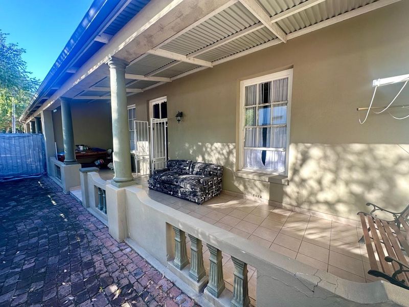 A covered patio area featuring tiled flooring, concrete balustrades, and structural columns, providing a sheltered outdoor space for relaxation.