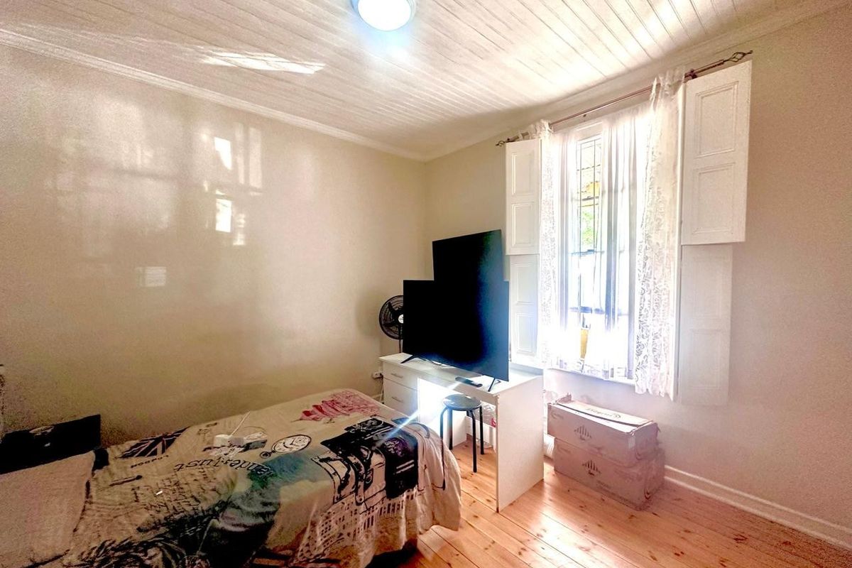 A bedroom featuring timber flooring, a timber panelled ceiling, and classic internal window shutters, providing a cozy and character-filled living space.
