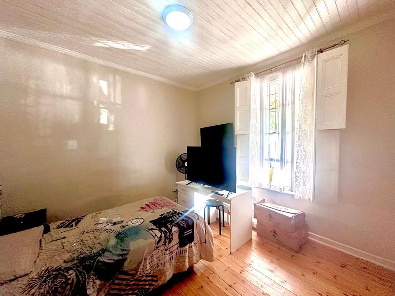 A bedroom featuring timber flooring, a timber panelled ceiling, and classic internal window shutters, providing a cozy and character-filled living space.