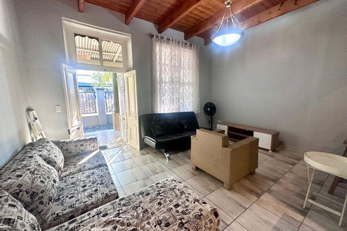 Living room featuring exposed timber ceiling beams, tiled flooring, and direct access to an outdoor patio area through double doors.