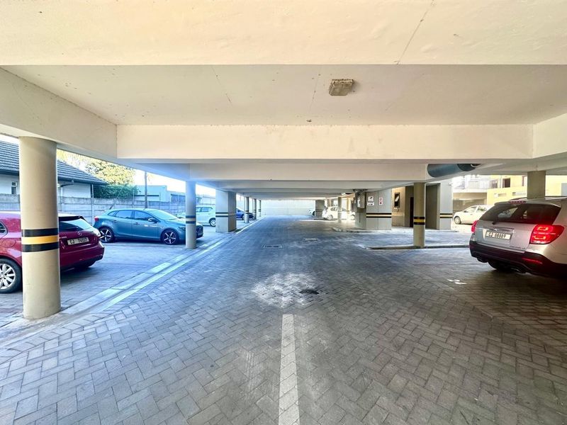 A covered parking garage area featuring concrete structural columns and paved flooring.