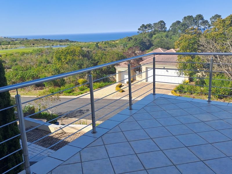 Spacious balcony featuring a modern stainless steel balustrade and tiled flooring, offering elevated views of the surrounding landscape and coastline.