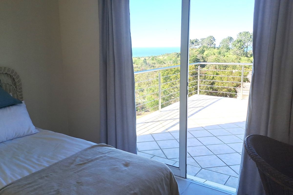 Bedroom featuring a sliding glass door that opens onto a tiled balcony with a stainless steel balustrade and scenic coastal views.