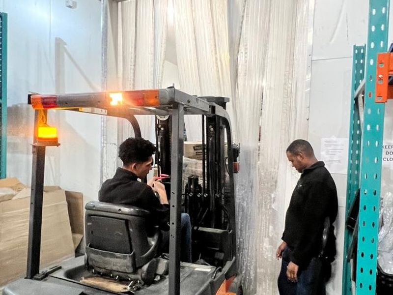 Industrial warehouse utility space featuring heavy-duty racking and a plastic strip curtain doorway for climate control.