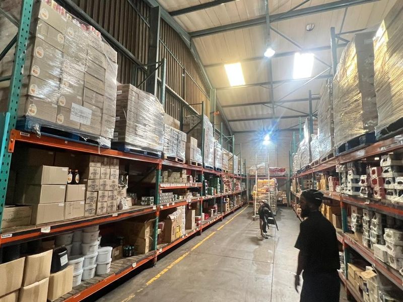Spacious industrial warehouse facility featuring high-bay lighting, exposed steel roof trusses, and extensive heavy-duty racking systems for efficient storage and logistics operations.