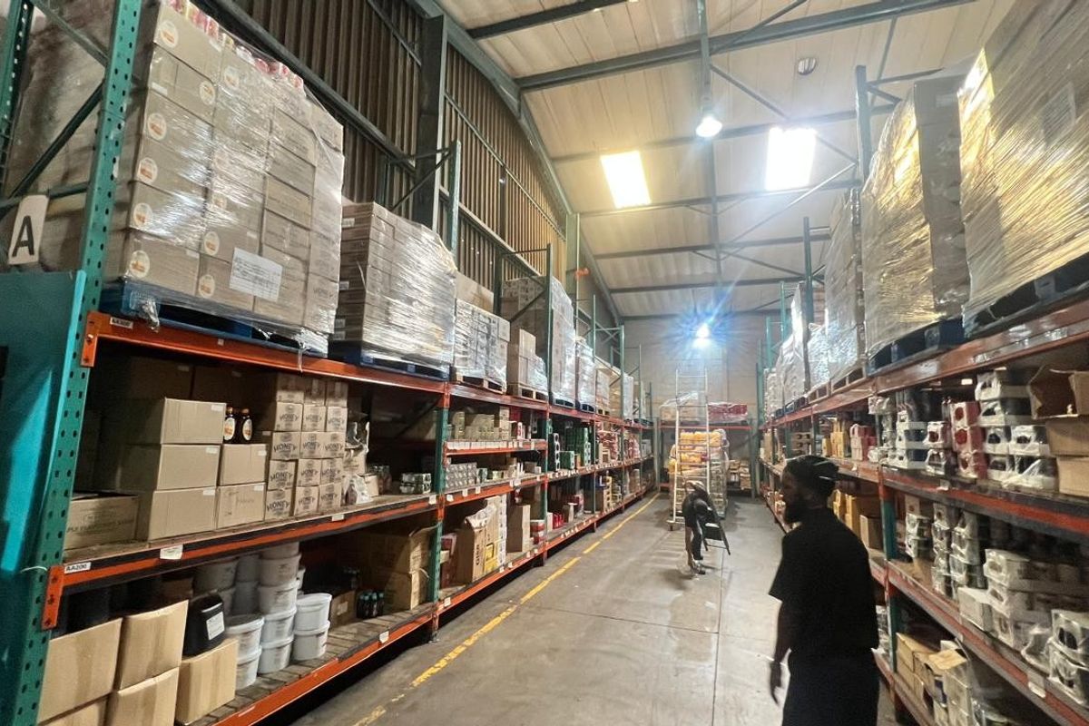 Spacious industrial warehouse facility featuring high-bay lighting, exposed steel roof trusses, and extensive heavy-duty racking systems for efficient storage and logistics operations.
