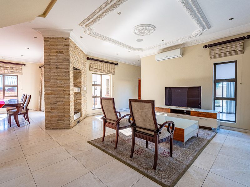 Spacious open-plan living and dining area featuring a striking stone-clad feature pillar, ornate ceiling detailing, and large windows providing ample natural light.
