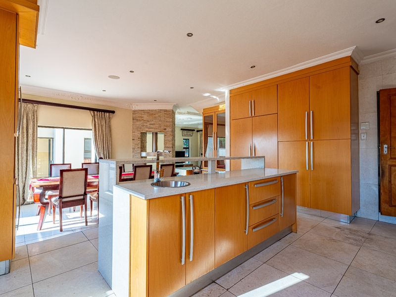 Open-plan living area featuring a kitchen island with stone countertops, extensive built-in cabinetry, and tiled flooring, seamlessly connecting to the dining space.