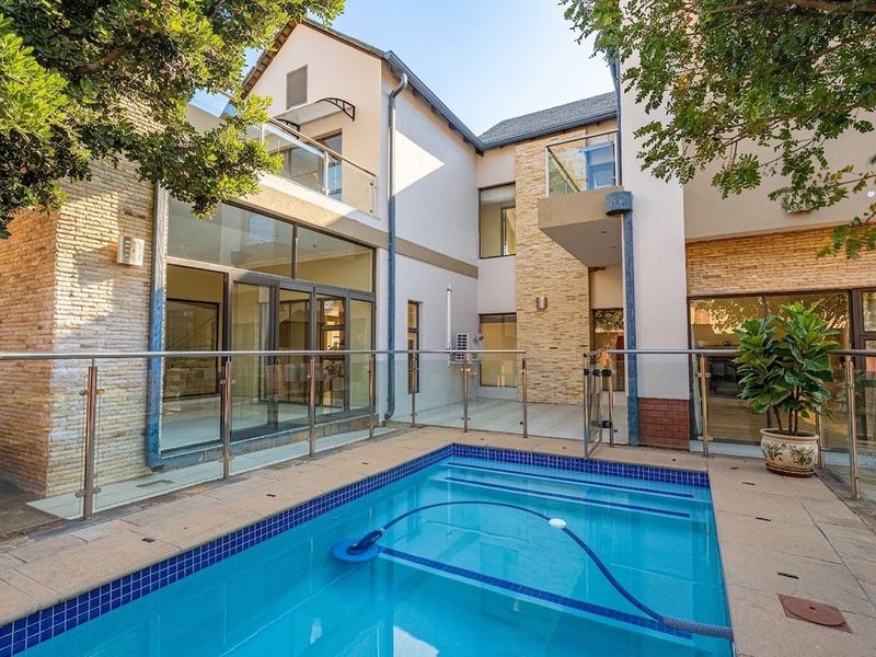 A well-maintained courtyard featuring a swimming pool, glass balustrades, and modern architectural finishes with direct access to the home's living areas.
