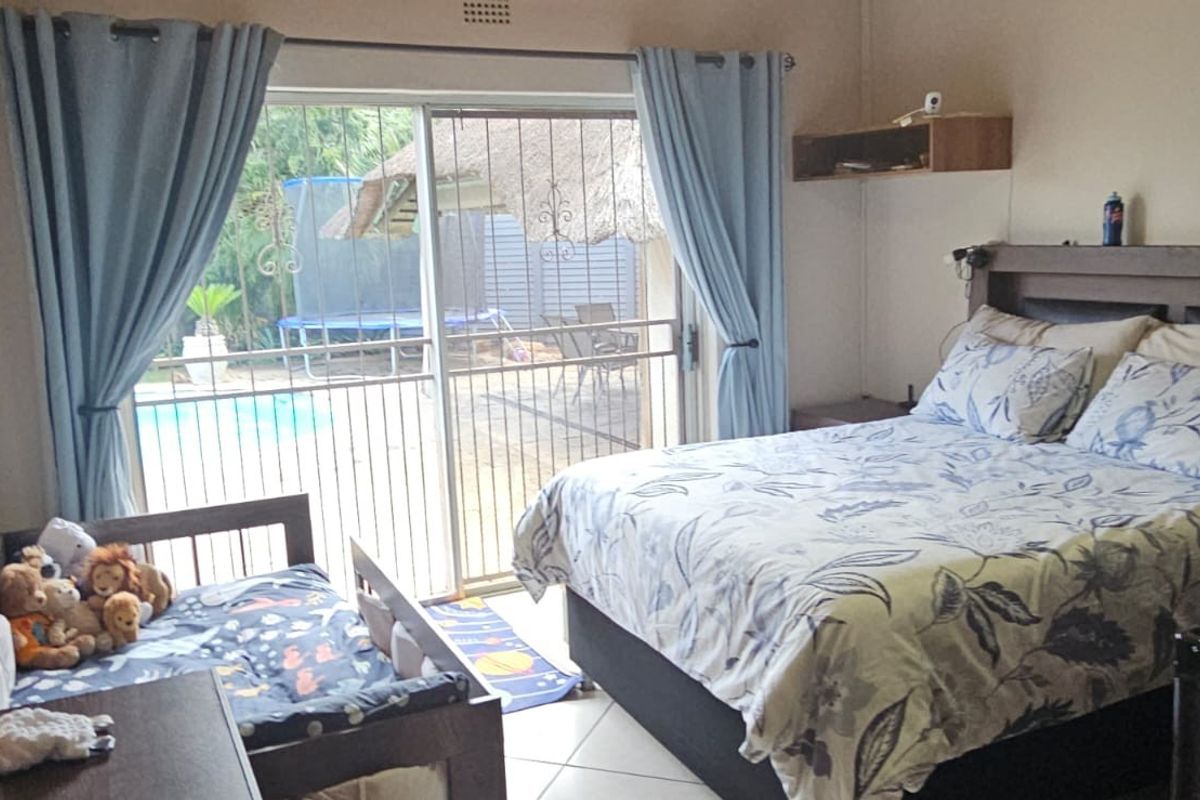 Spacious bedroom featuring tiled flooring and a large sliding glass door providing direct access to the outdoor pool area.