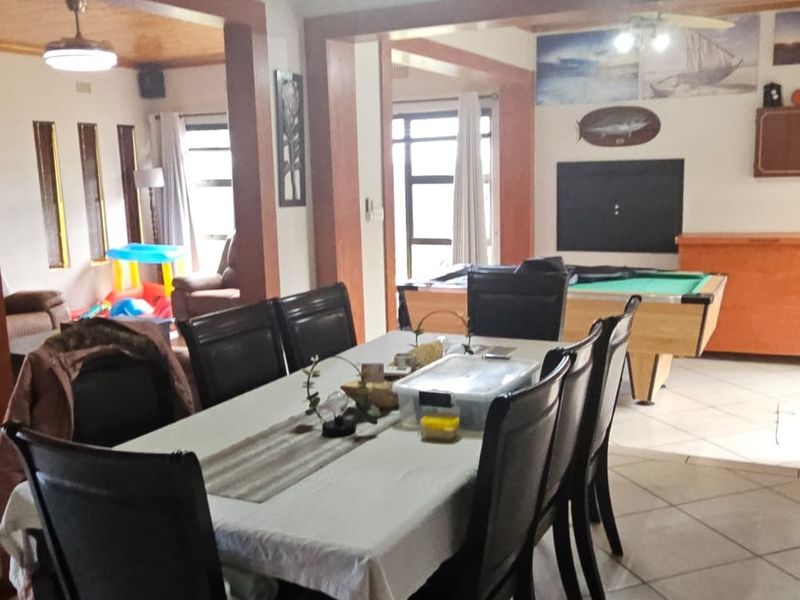 Spacious open-plan living and dining area featuring tiled flooring, timber ceiling accents, and a functional layout connecting multiple living zones.