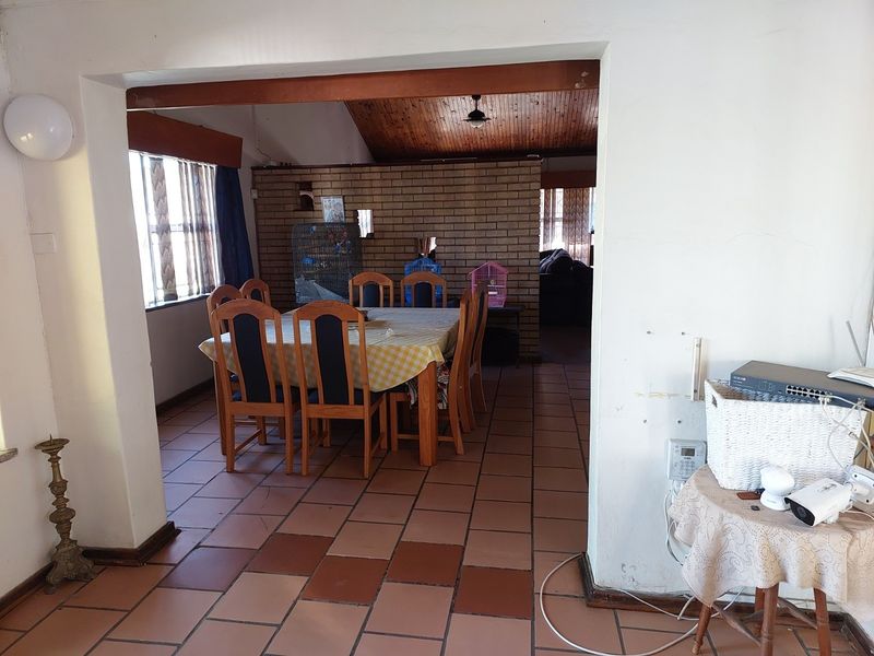 Dining area featuring terracotta floor tiles, a brick feature wall, and an exposed timber ceiling, offering a rustic aesthetic with potential for modernization.