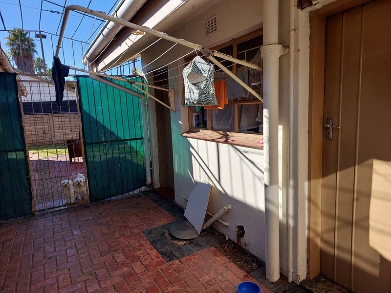 Rear exterior area featuring brick paving, a wall-mounted clothesline, and access to the property via a side door.
