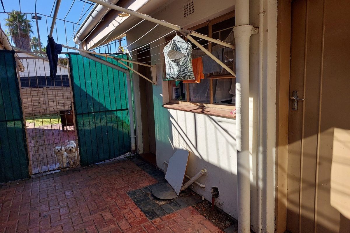 Rear exterior area featuring brick paving, a wall-mounted clothesline, and access to the property via a side door.