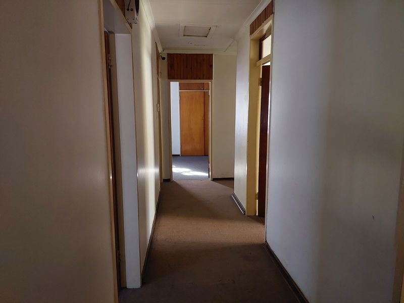 A functional hallway featuring built-in cupboards, timber door frames, and carpeted flooring, providing access to multiple rooms within the home.