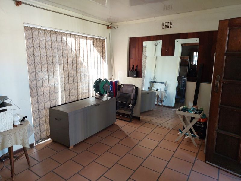 A living area featuring terracotta floor tiles, wood paneling, and built-in wall mirrors, offering a dated aesthetic ready for modernization.