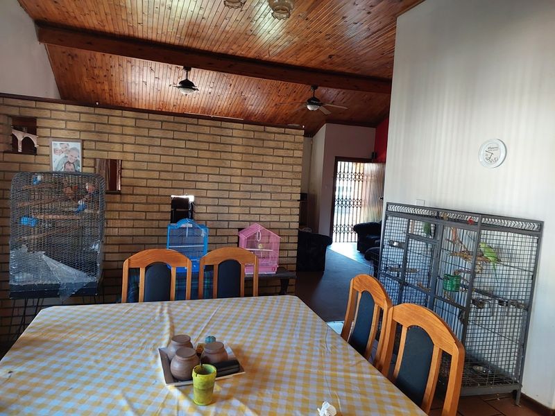 Dining area featuring a rustic exposed timber ceiling, exposed brick feature wall, and ceiling fans, providing a warm and traditional atmosphere.