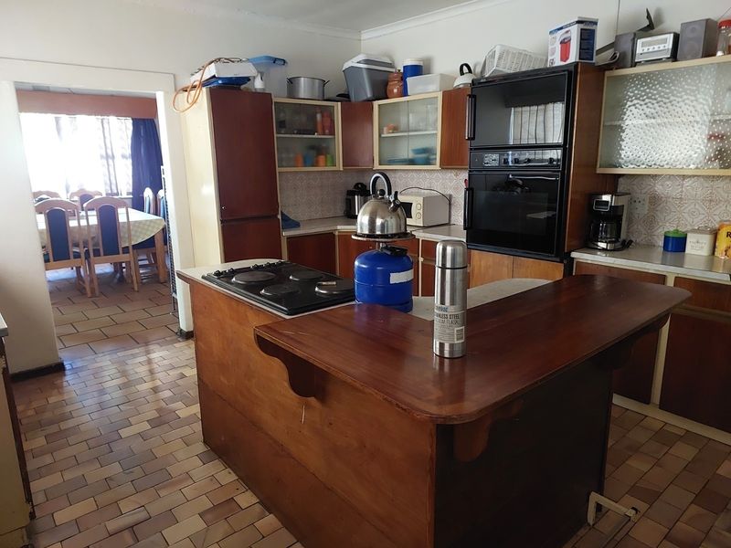 A dated kitchen featuring wooden cabinetry, a built-in double oven, electric hob, and tiled flooring, offering significant potential for a modern renovation.