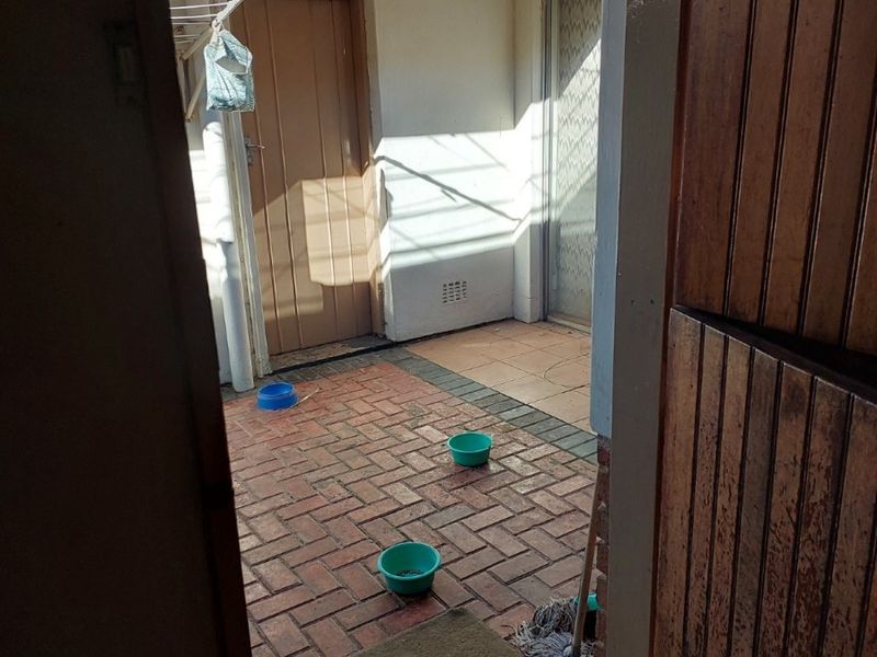 A functional outdoor patio area featuring brick paving, tiled sections, and a wall-mounted clothesline, providing a practical space for utility or relaxation.