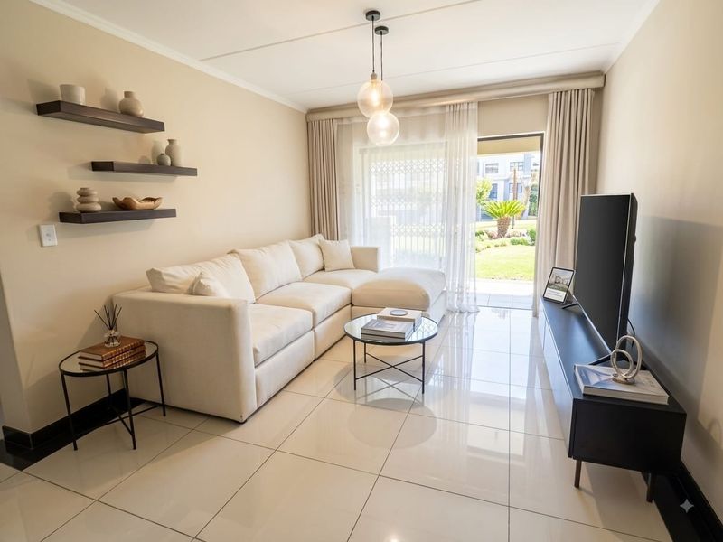 Modern living room featuring polished porcelain floor tiles, neutral wall tones, and a sliding glass door providing direct access to the garden area.