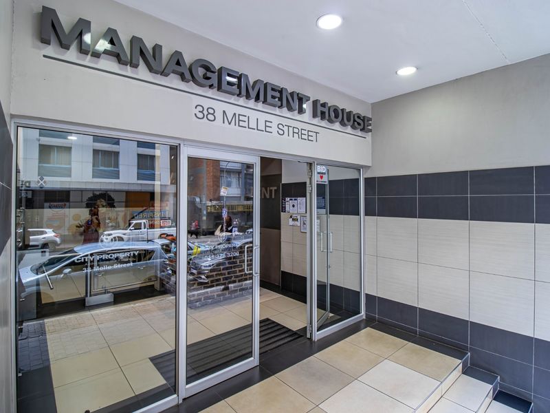 The entrance to Management House at 38 Melle Street features glass doors, modern tiled wall finishes, and recessed ceiling lighting in a clean commercial lobby.