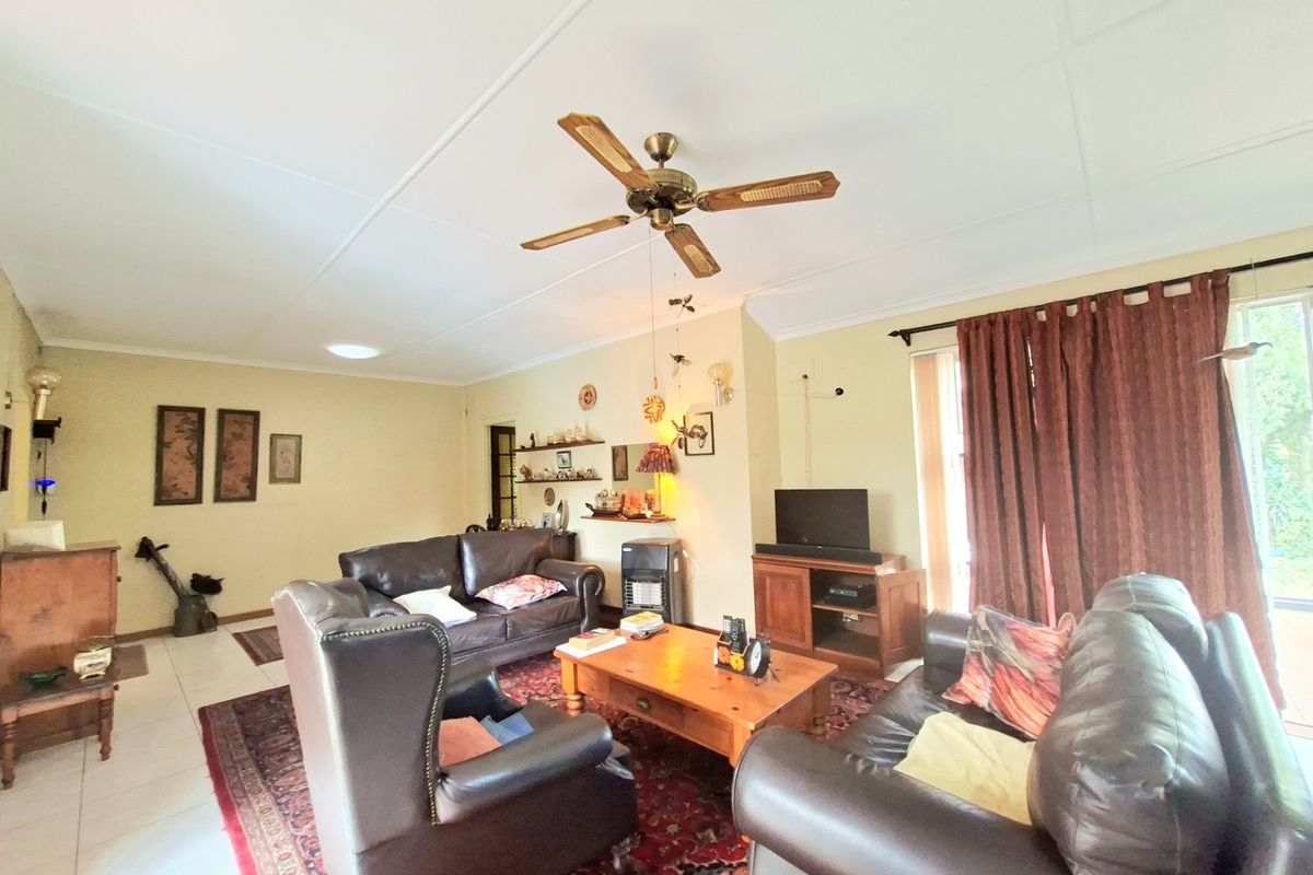 A spacious living room featuring tiled flooring, a ceiling fan, and direct access to the outdoors through a sliding glass door.