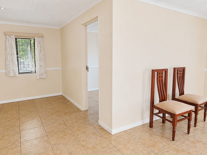A bright, neutral living area featuring tiled flooring, recessed lighting, and decorative chair rail molding, offering a clean and versatile space.