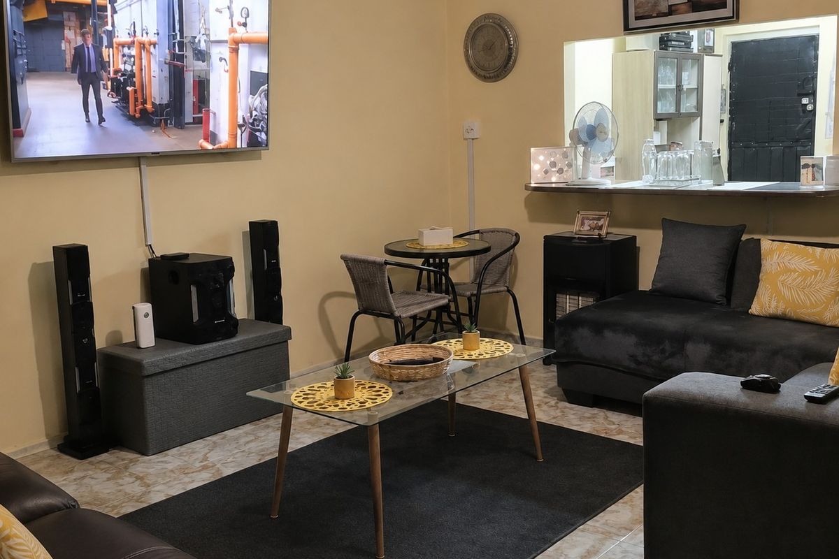 A living room featuring tiled flooring and a convenient pass-through window with a breakfast bar connecting to the adjacent space.
