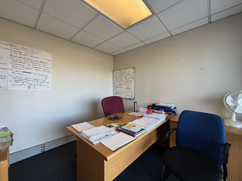 A functional office space featuring a suspended ceiling with recessed lighting and carpeted flooring, suitable for professional use.
