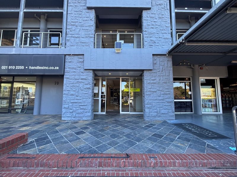 Front entrance of a commercial office building featuring stone cladding, glass doors, and slate tile flooring at the main access point.