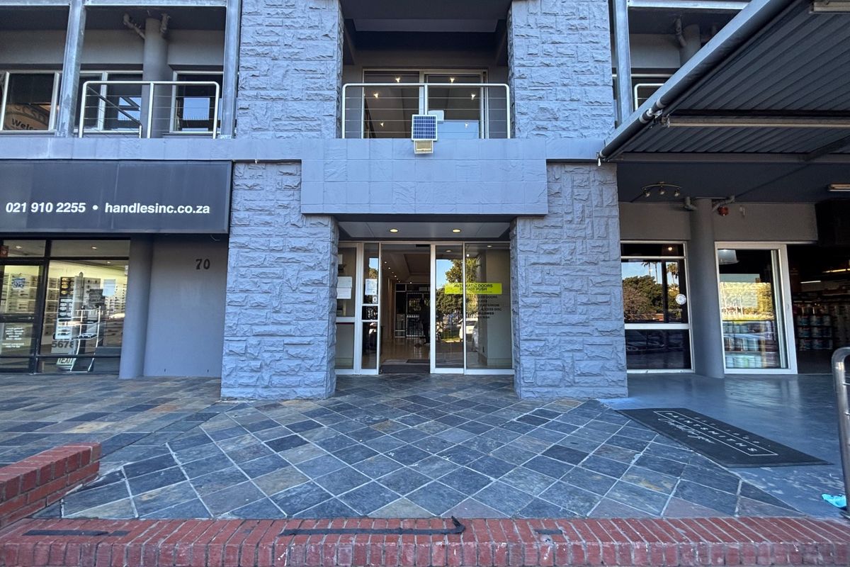 Front entrance of a commercial office building featuring stone cladding, glass doors, and slate tile flooring at the main access point.