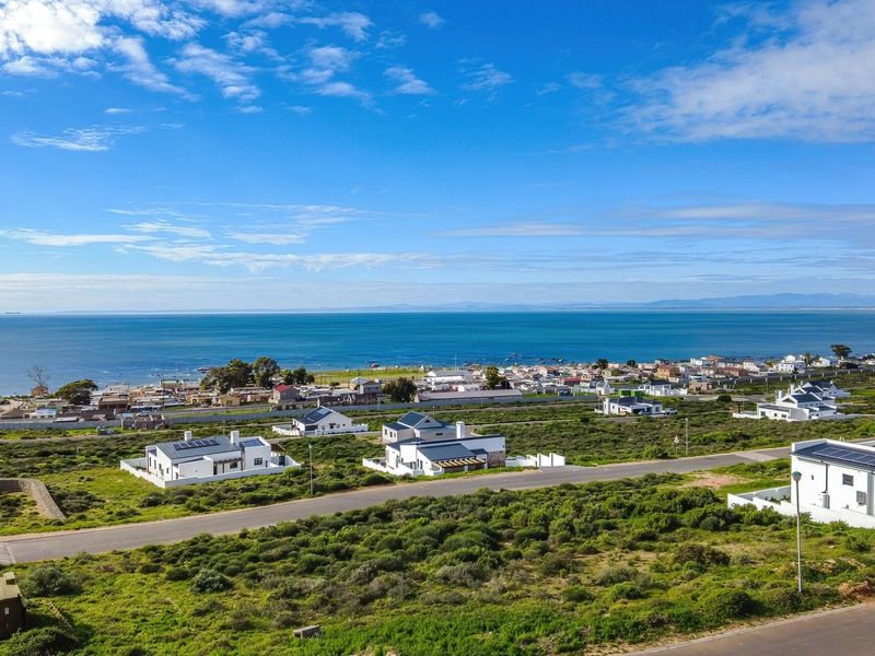 An aerial view of a coastal residential development featuring paved roads and modern homes overlooking the ocean.