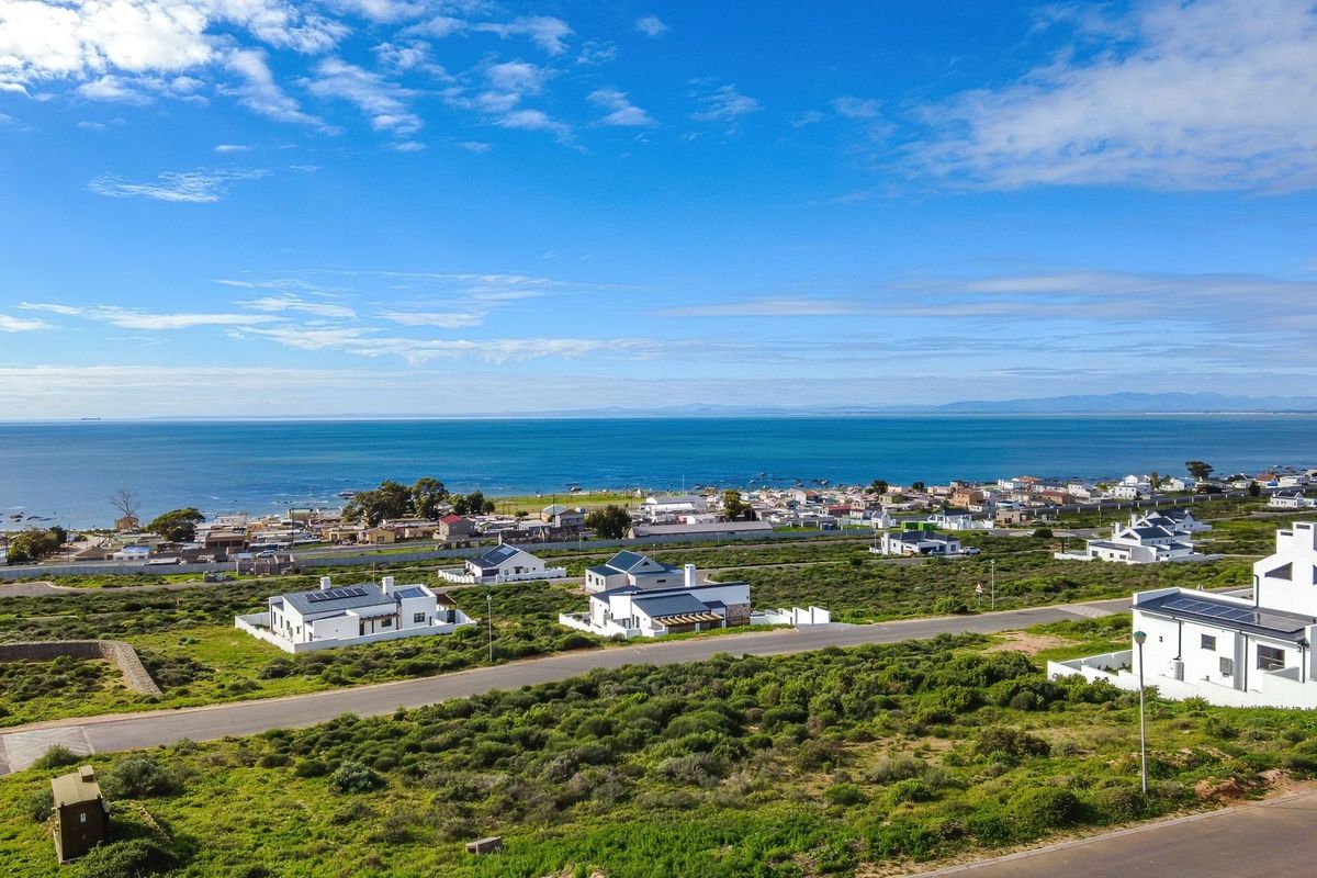 An aerial view of a coastal residential development featuring paved roads and modern homes overlooking the ocean.