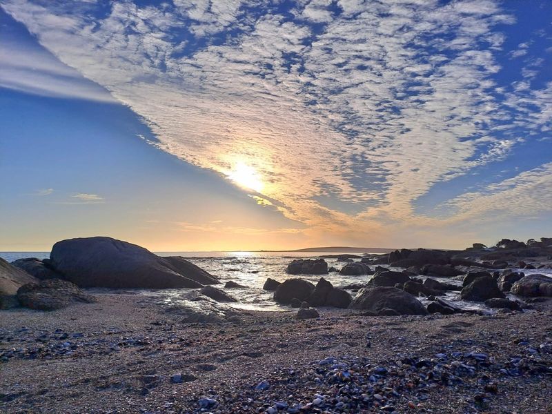 A scenic coastal view featuring a rocky shoreline and sunset over the ocean, highlighting the natural landscape of the property.