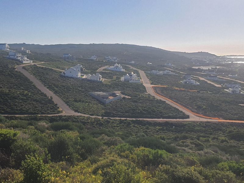 An elevated aerial view of a residential estate development featuring paved roads and surrounding coastal vegetation.