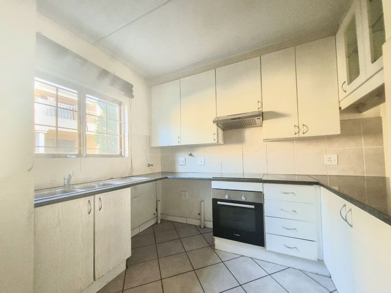 A functional kitchen featuring white built-in cabinetry, granite countertops, a built-in oven with hob, and tiled flooring, offering a clean canvas for updates.