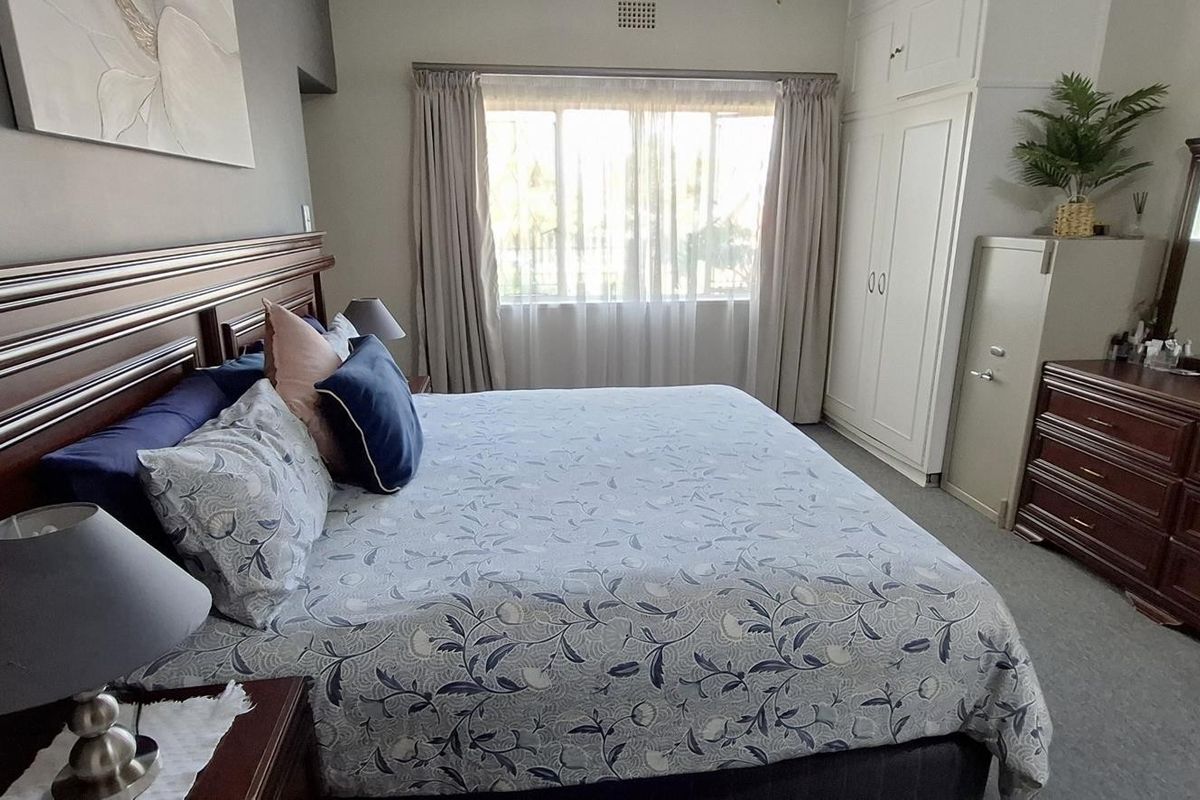 A well-maintained bedroom featuring built-in cupboards, neutral wall tones, and carpeted flooring, offering a comfortable and functional living space.