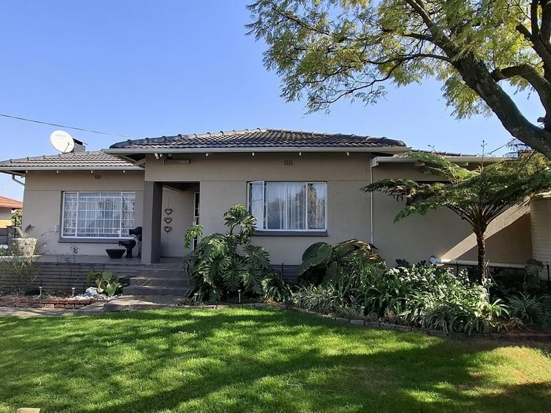 A well-maintained single-story residential home featuring a tiled roof, secure window bars, and a landscaped front garden with a paved driveway.