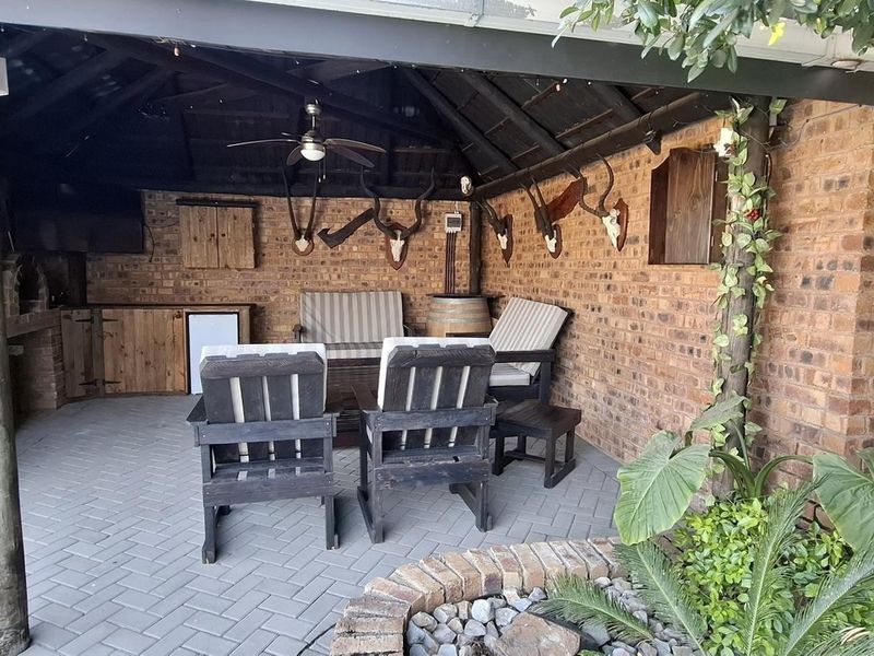 Covered outdoor patio featuring a built-in brick braai, exposed timber roof structure, and brick paving, ideal for outdoor entertaining.