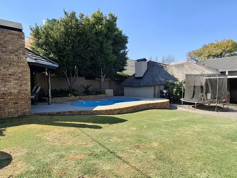 Outdoor entertainment area featuring a swimming pool, brick chimney, and paved patio space set within a private garden.