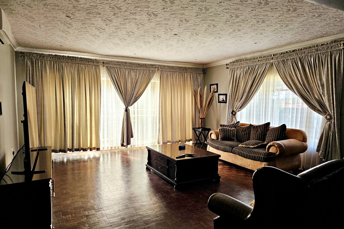 Spacious living room featuring classic parquet flooring, a decorative textured ceiling, and large sliding glass doors that provide ample natural light.
