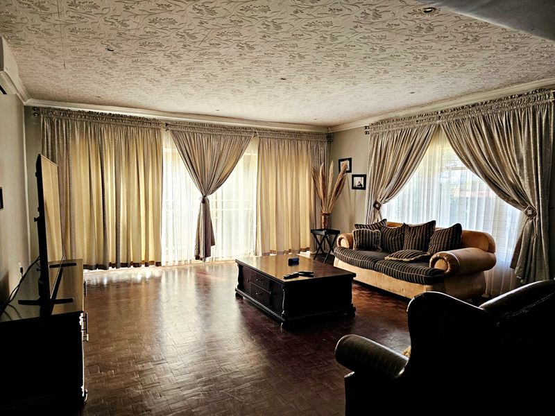 Spacious living room featuring classic parquet flooring, a decorative textured ceiling, and large sliding glass doors that provide ample natural light.