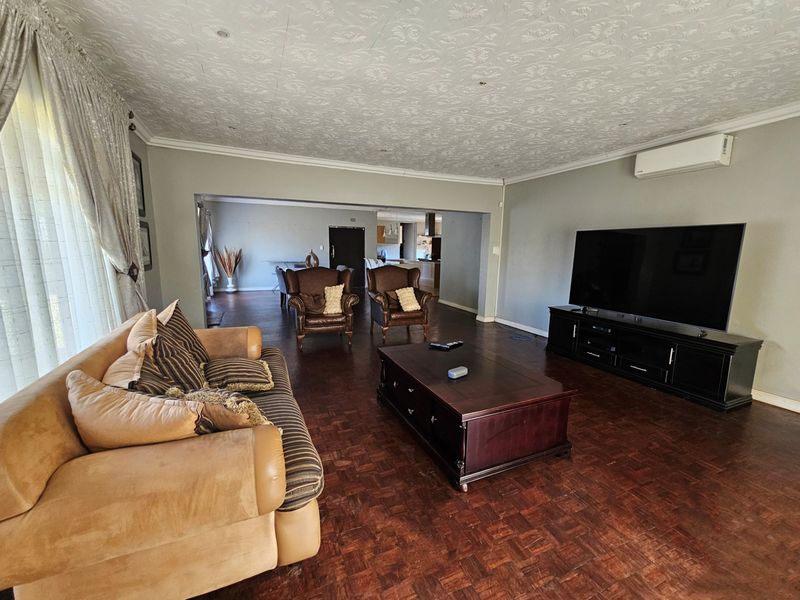 Spacious open-plan living area featuring classic parquet flooring, a textured ceiling, and a wall-mounted air conditioning unit.