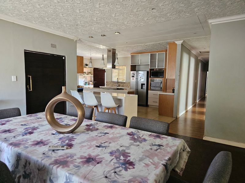 Open-plan living and dining area featuring a modern kitchen with a central island, built-in cabinetry, and a mix of tiled and laminate flooring.