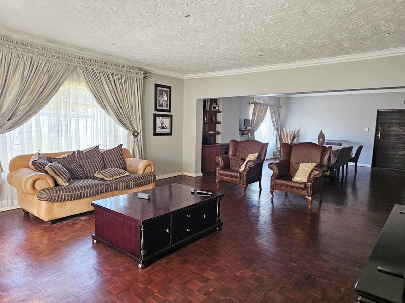 Spacious open-plan living and dining area featuring classic parquet flooring and a decorative pressed metal ceiling, offering a versatile layout for family living.