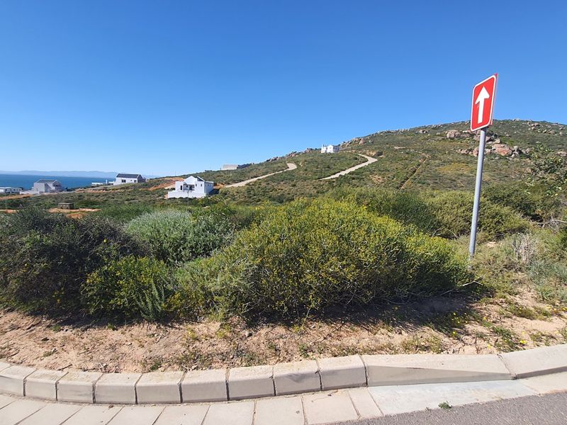 A view of the street approach and surrounding landscape, showing the natural terrain and local road infrastructure.