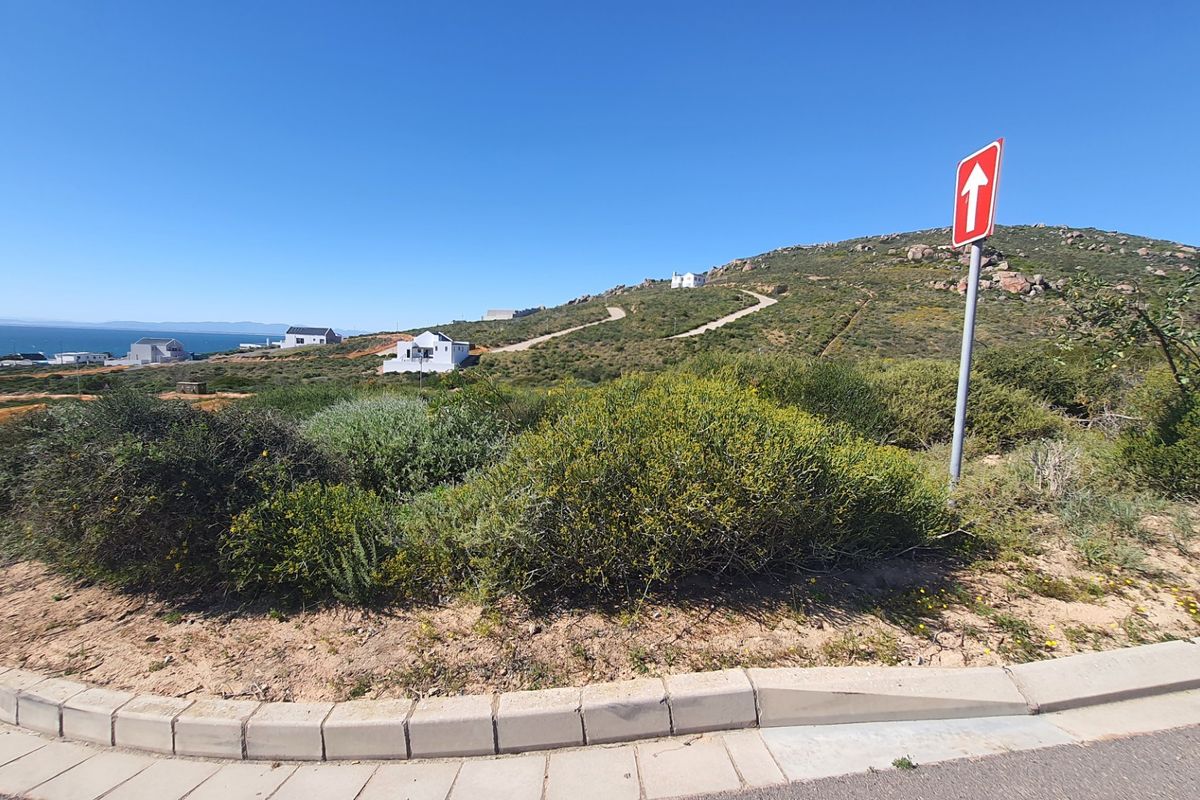 A view of the street approach and surrounding landscape, showing the natural terrain and local road infrastructure.