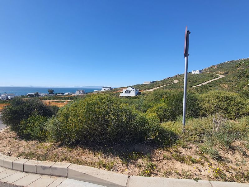 A scenic view of the coastal landscape and surrounding residential area from the street level of the vacant land.