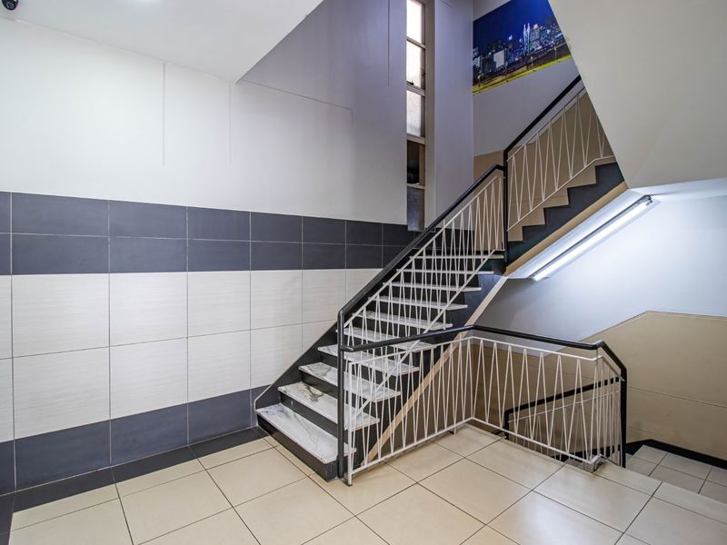 A clean, well-maintained commercial stairwell featuring tiled flooring, modern wall tiling, and a secure metal balustrade.